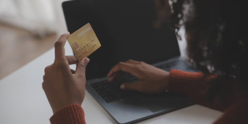 Person holding credit card and typing information into laptop
