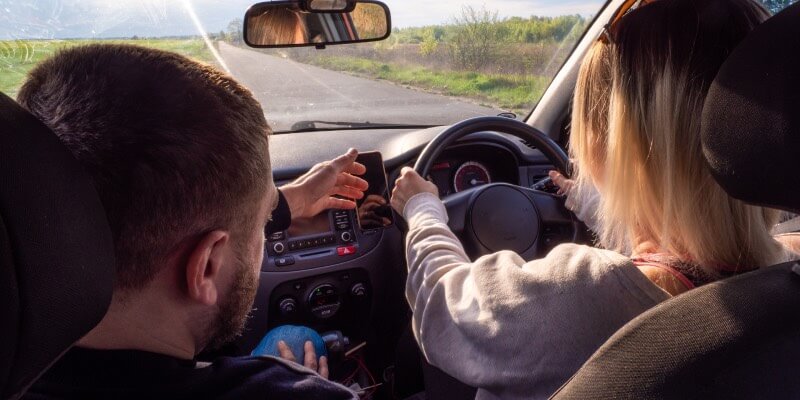 Instructor leaning towards steering wheel whilst learner drives car