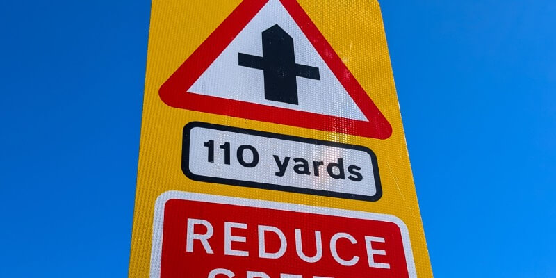 Sign with crossroad displayed and 'reduce speed now'