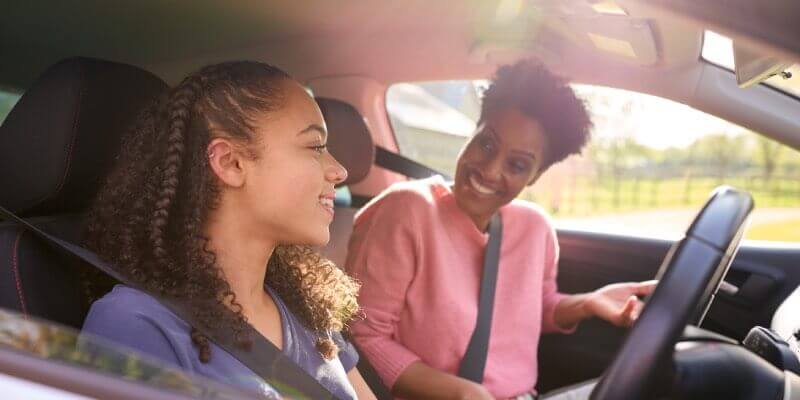 Two girls in the car smiling at each other